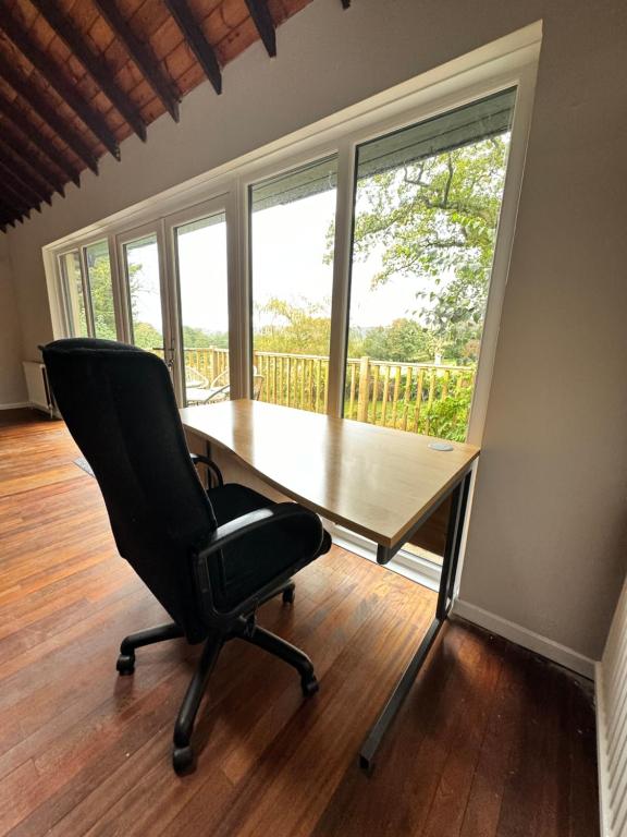 a desk with a chair in a room with windows at Plasbach Cottage in Llandeilo