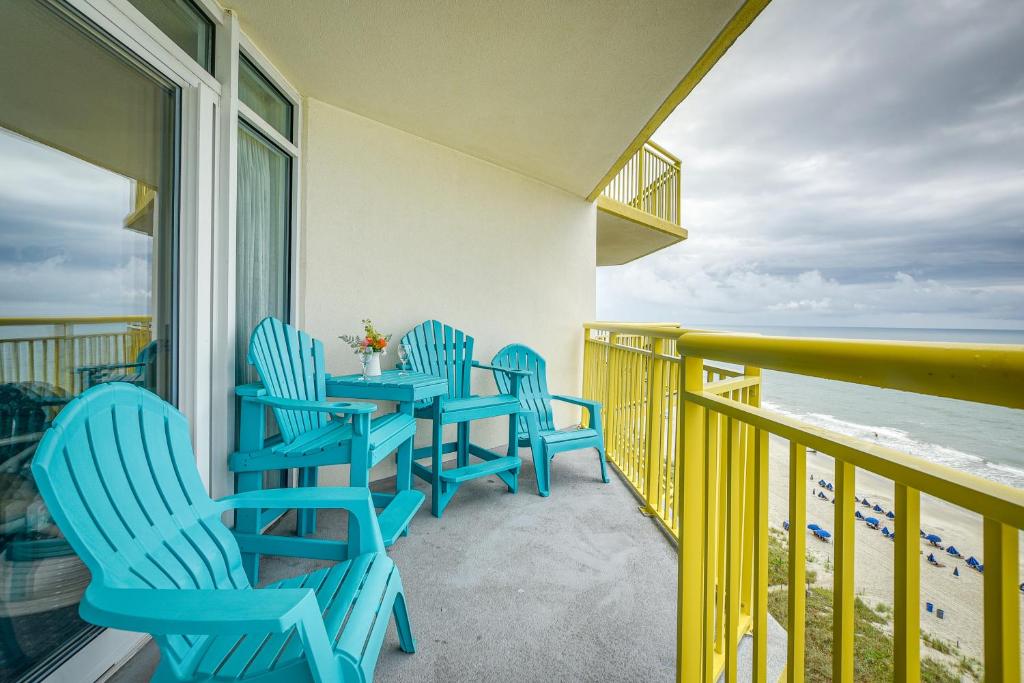 a balcony with blue chairs and a table and the ocean at 2 Mi to Barefoot Landing Condo with Beach Access! in Myrtle Beach