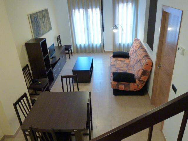 sala de estar con mesa, sofá y silla en Apartamentos Puerta Muralla, en Teruel