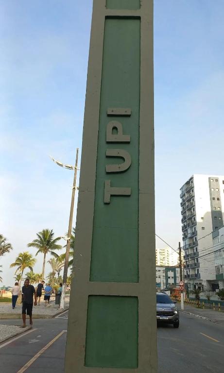 a green sign on the side of a street at Ap Vila Tupi PG in Praia Grande