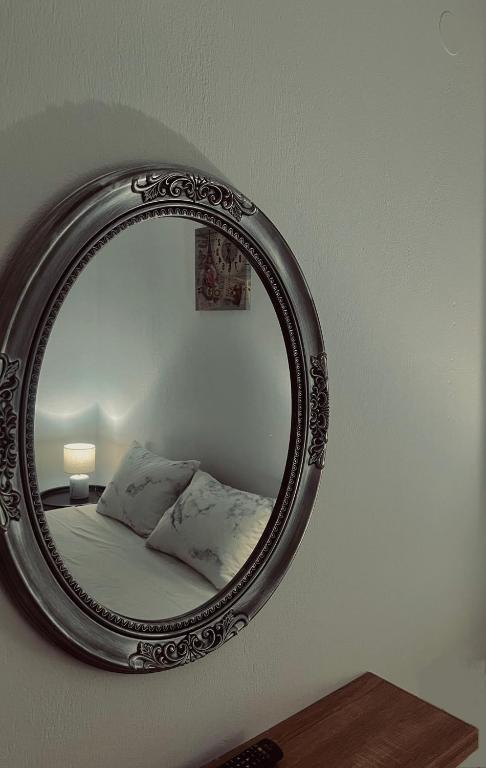a mirror on a wall with a bed in a room at Family House Dim in Ioannina