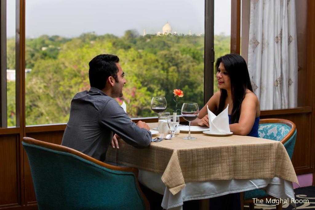 a man and woman sitting at a table with wine glasses at Hotel Clarks Shiraz in Agra
