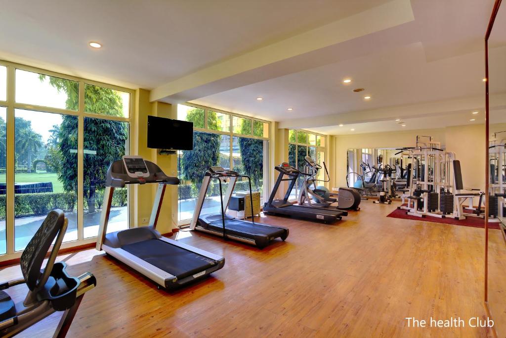 a gym with several treadmills and elliptical machines at Hotel Clarks Shiraz in Agra