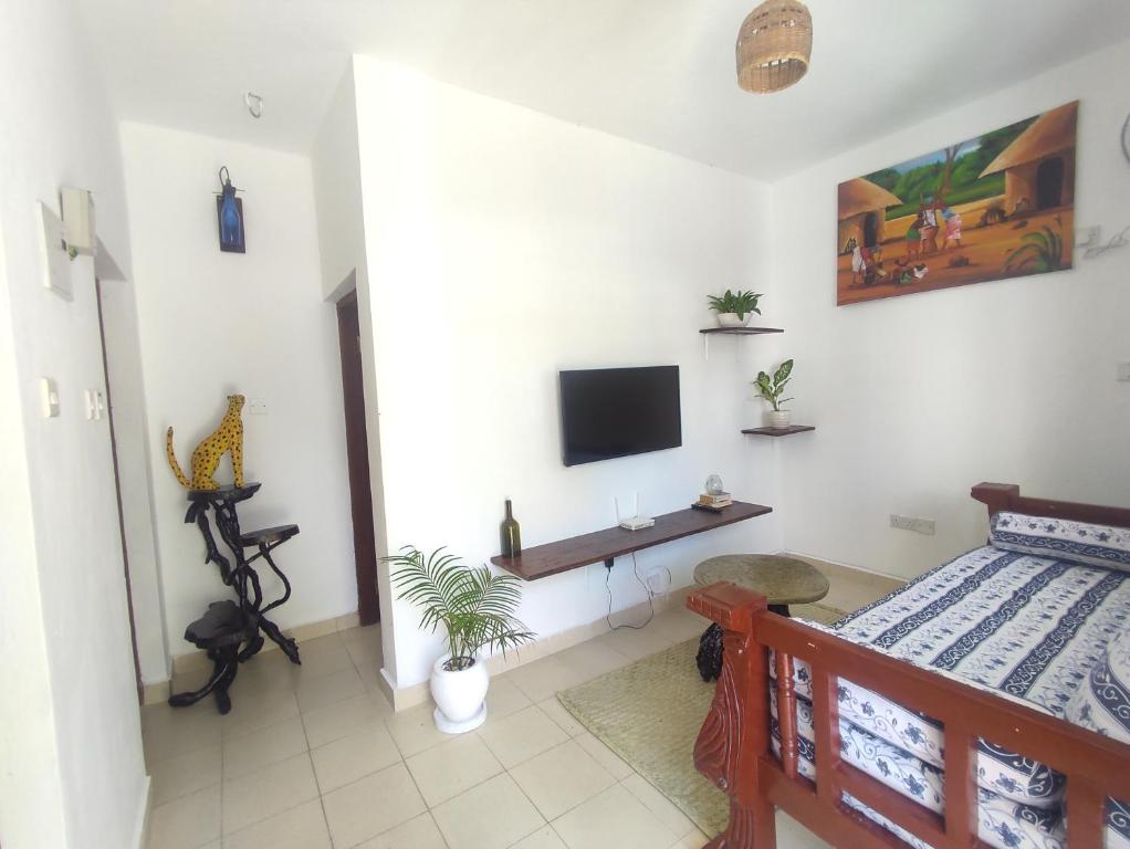 Un dormitorio con una cama y un televisor en la pared. en Tajari Diani Beach Condo, en Galu