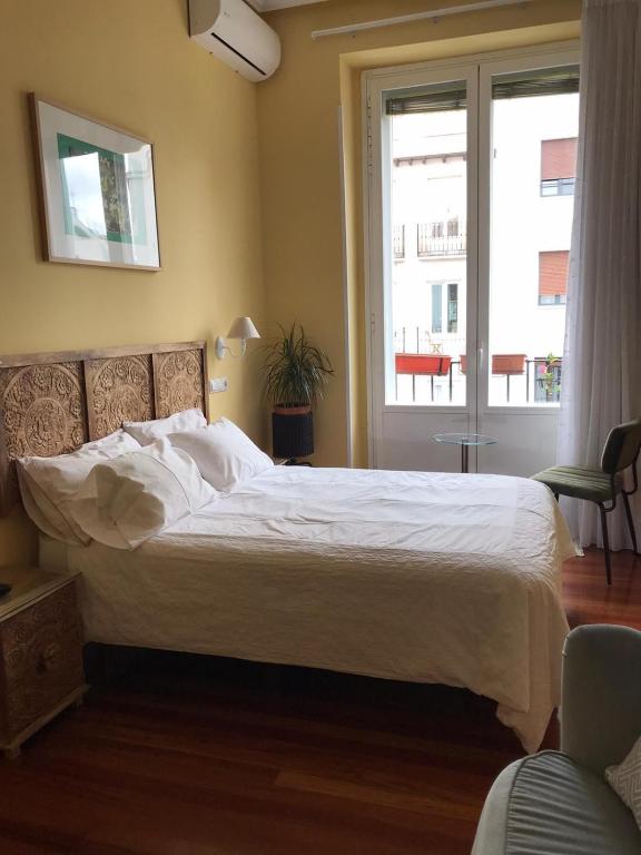 a bedroom with a large white bed and a window at La casa de la escritora in Madrid