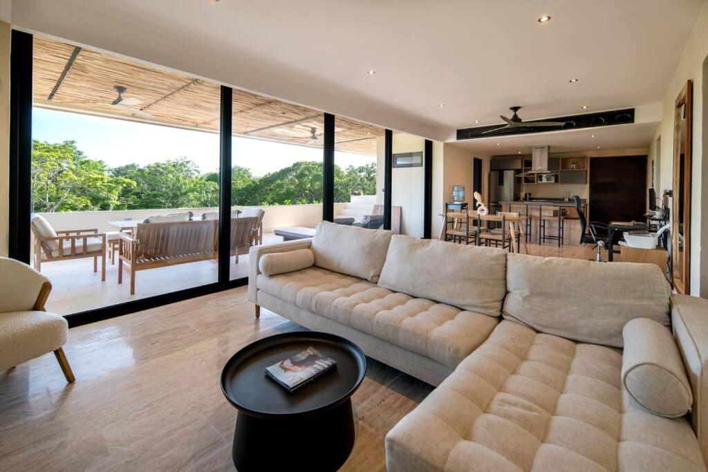 a living room with a large couch and a kitchen at Jungle Sky Loft in Tulum