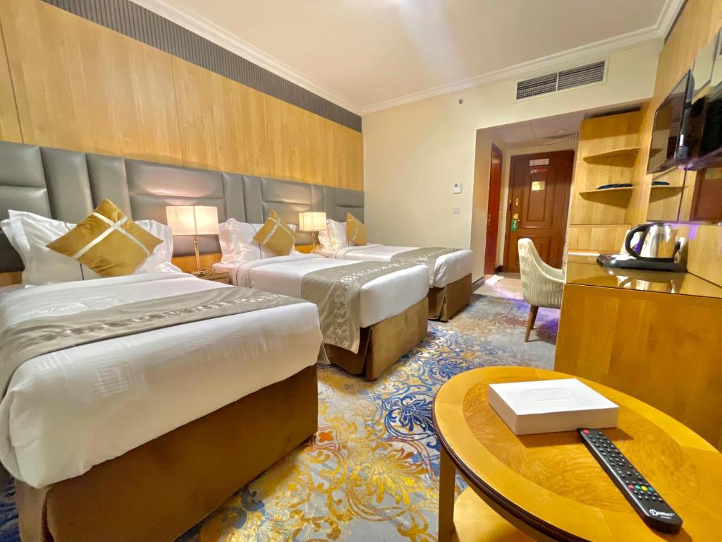 una habitación de hotel con dos camas y una mesa en Zowar Alalami Hotel, en Medina