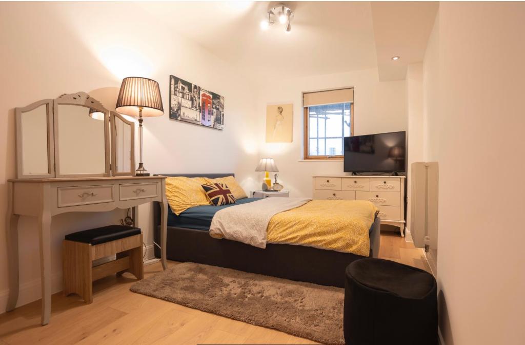 a bedroom with a bed and a desk and a television at COSY RIVERVIEW-LONDON EXCEL CENTRE-O2 ARENA in London