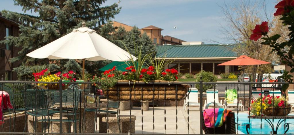 a patio with an umbrella and chairs and flowers at The Foothills Inn in Rapid City