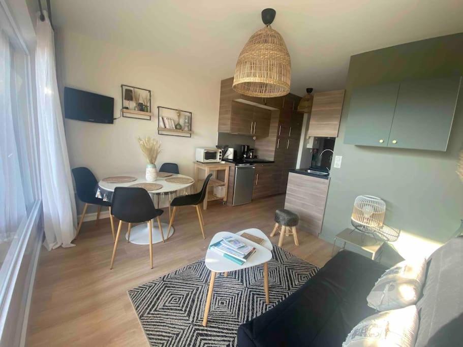 un salon avec un canapé et une table et une cuisine dans l'établissement Appartement bord de mer, à Dinard