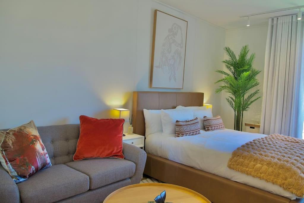 a living room with a bed and a couch at Chic Minimalist City Retreat in Cape Town