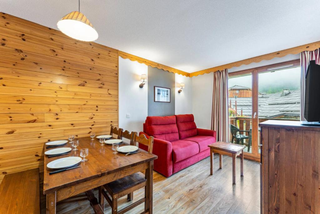 un salon avec une table et un canapé rouge dans l'établissement Résidence Les Hauts De Preclaux - Appartement cosy pour 6 au coeur des Orres 1800 MAE-9951, aux Orres