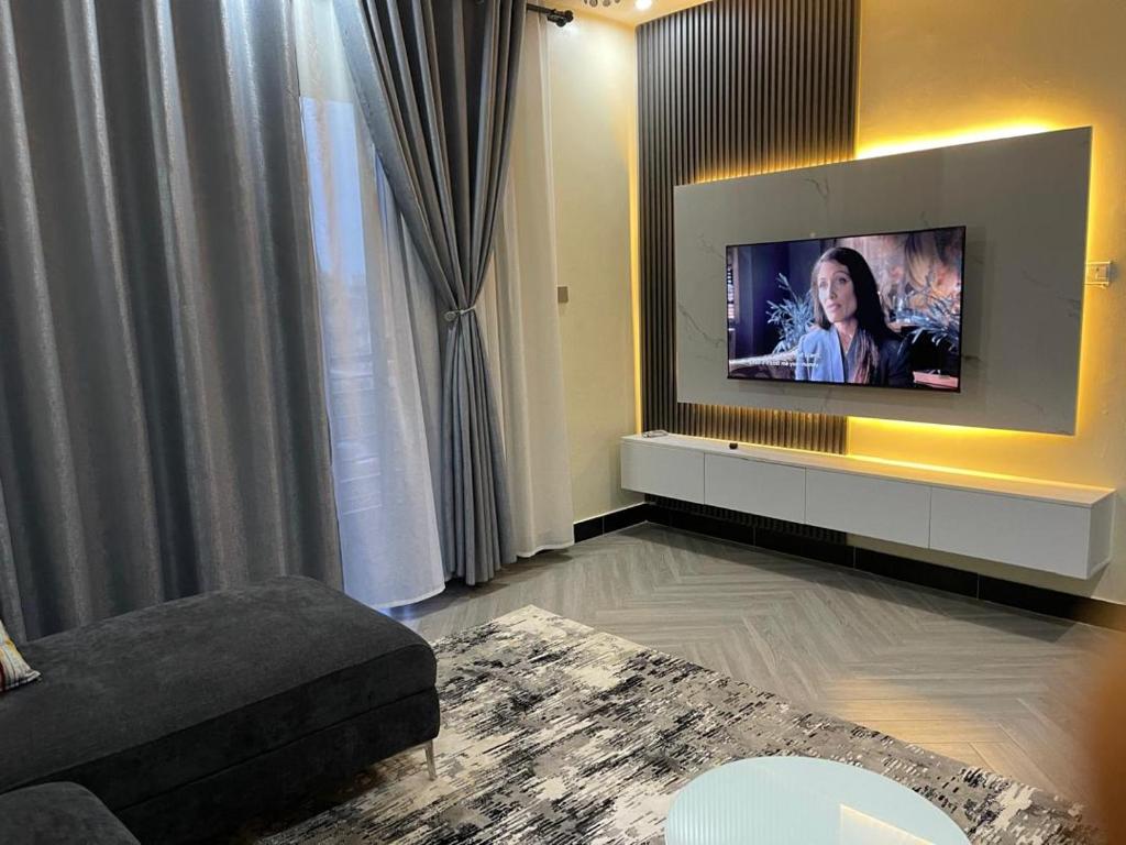 Una sala de estar con un televisor de pantalla plana en una pared. en Luxury Budgethomes Bukoto, en Kampala