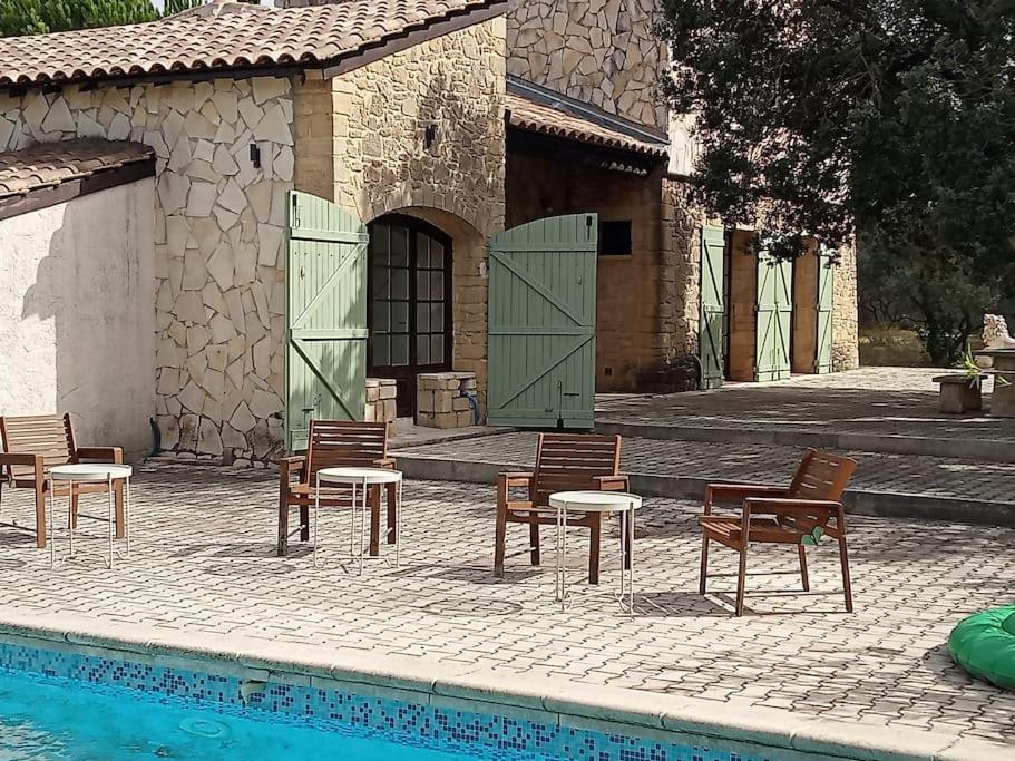 - un groupe de chaises et de tables à côté d'une piscine dans l'établissement Mas intérieur rénové 4 chambres piscine, à Castillon-du-Gard