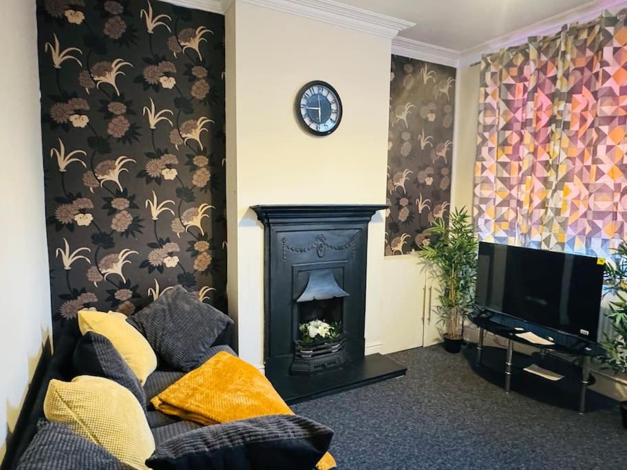 sala de estar con chimenea y reloj en la pared en Cosy 2 bedroom house in Leicester- entire house, sleeps 5, en Leicester