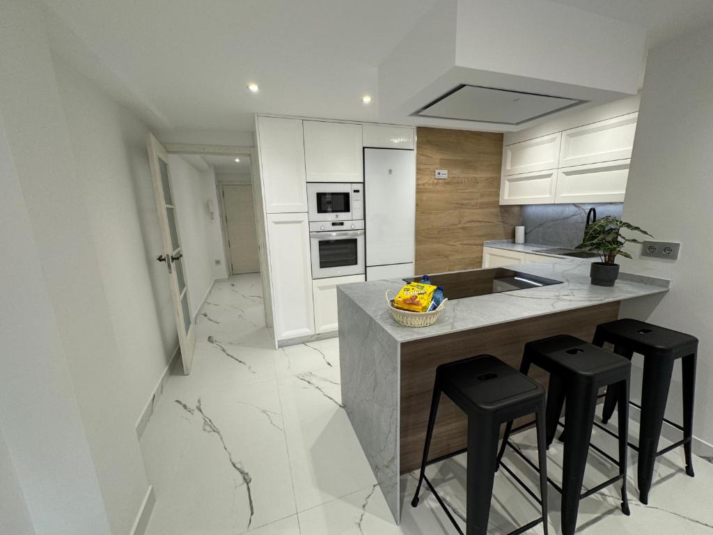 eine Küche mit weißen Schränken und einer Theke mit Stühlen in der Unterkunft Boabdil Luxury home in Córdoba