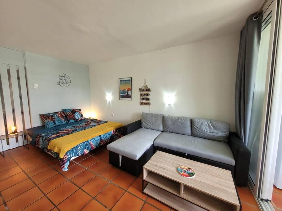 a living room with a couch and a bed at Grand studio les pieds dans l'eau! in Saint-François