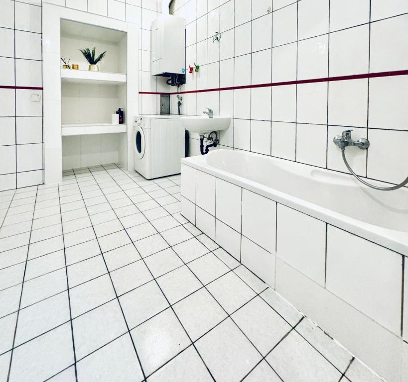 ein weiß gefliestes Bad mit einer Badewanne und einem Waschbecken in der Unterkunft 5BR Shared Apt Ideal for Groups 7 Min to Westbahnhof in Wien