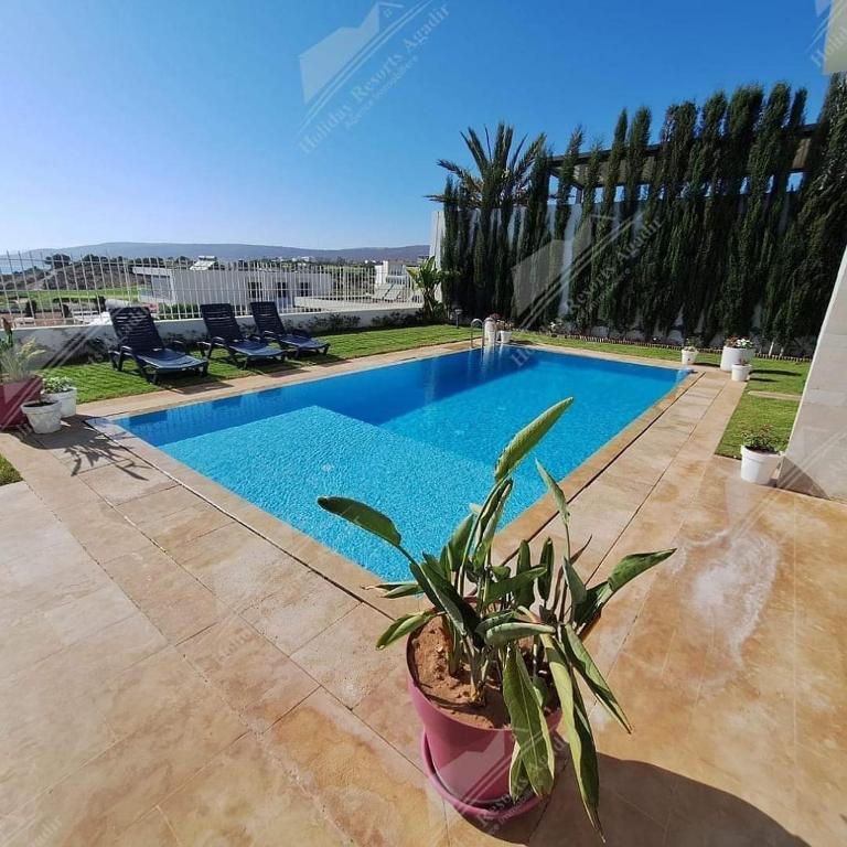 a potted plant sitting next to a swimming pool at Blue Sky 4 Bedroom Villa Taghazout Bay Amda in Taghazout