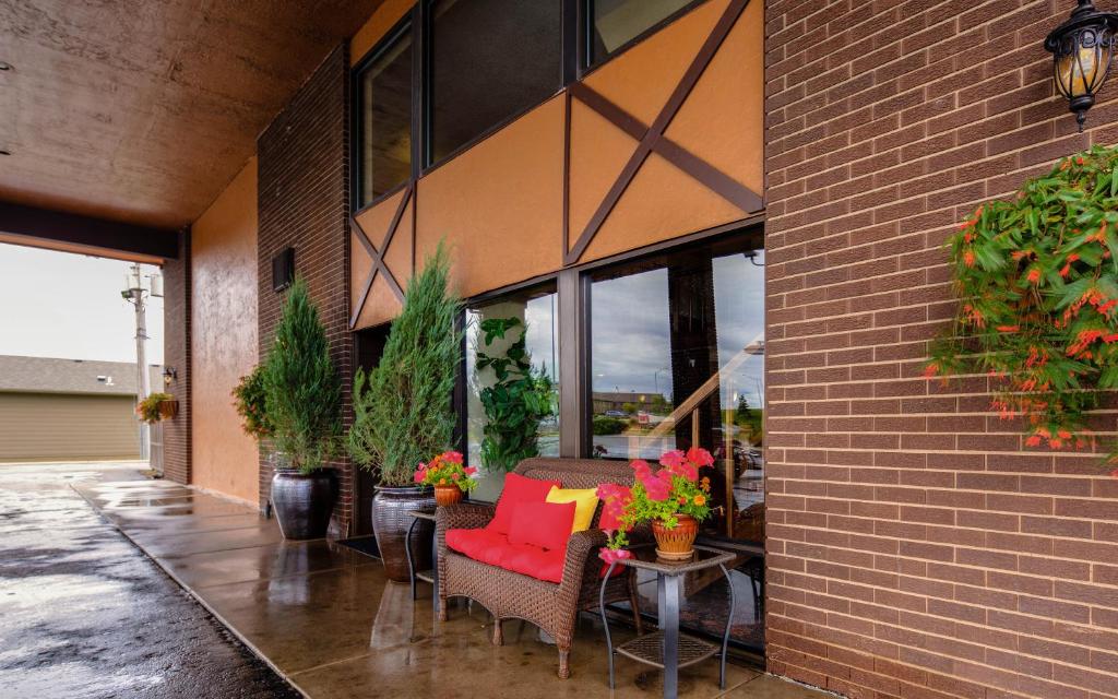 a patio with a red couch and chairs and plants at The Foothills Inn in Rapid City