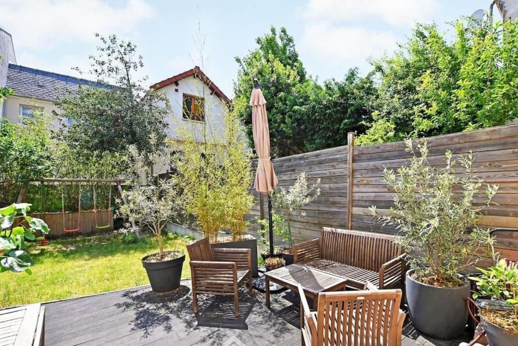 un patio avec une table, des chaises et un parasol dans l'établissement Maison familiale avec parking proche Paris et Parc des expositions de Villepinte, à Montreuil
