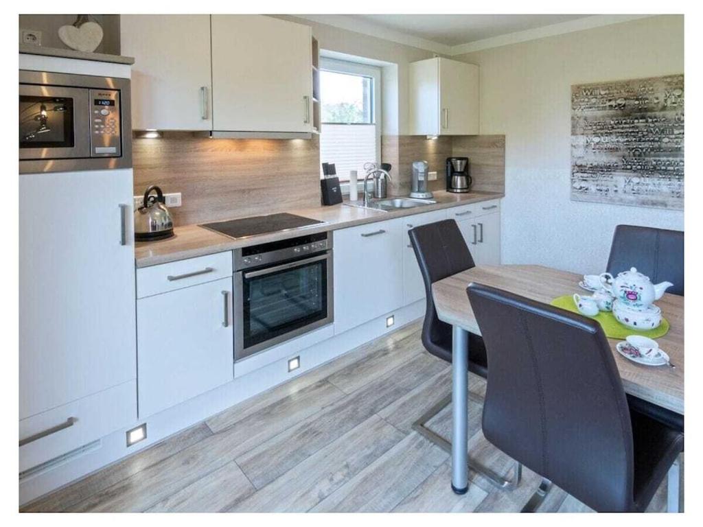 a kitchen with white cabinets and a table with chairs at Holiday apartment Palstek in Norddeich