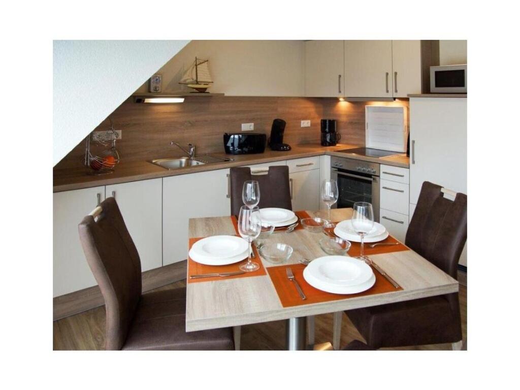a kitchen with a table with plates and wine glasses at Holiday apartment Kettenstek in Norddeich