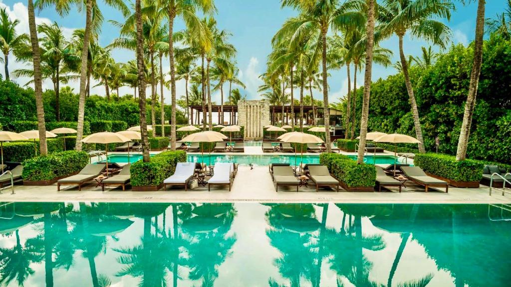 a pool with chairs and umbrellas and palm trees at THE SETAI 5 STARS HOTEL-RESIDENCE MIAMI BEACH OCEANVIEW 2 Bedroom UNIQUE in Miami Beach