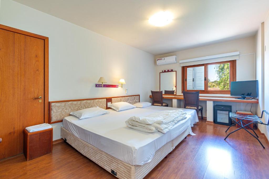 格拉玛多Suíte no Wish Resort Centro de Gramado的一间带床和书桌的卧室和厨房