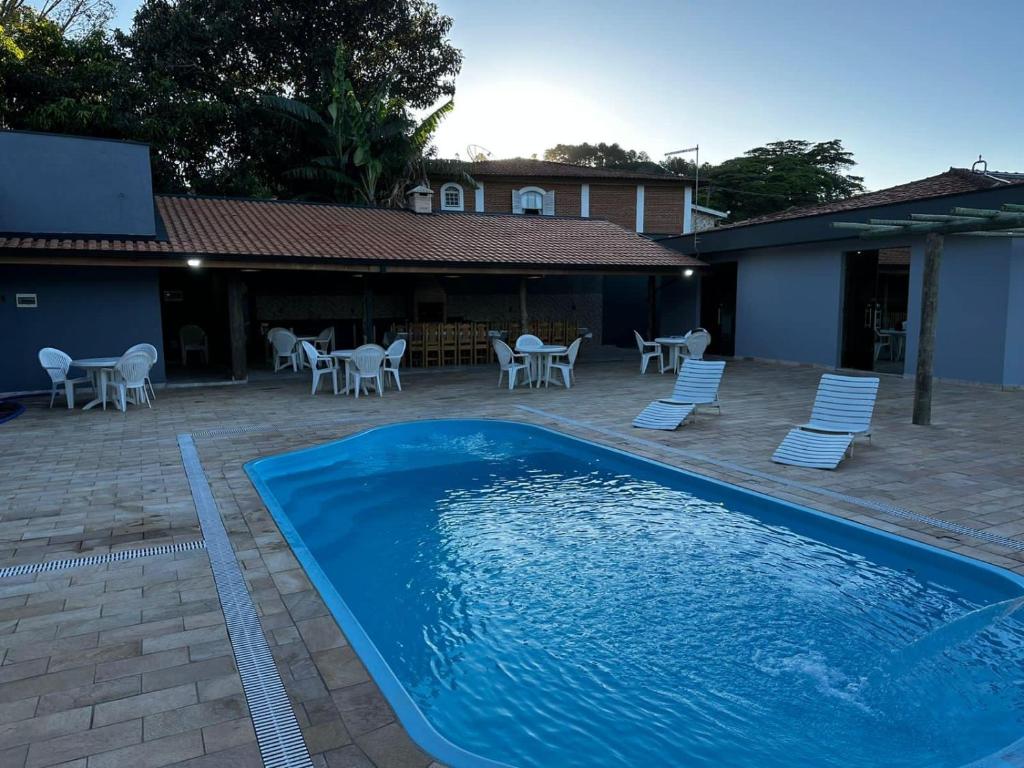 a large blue swimming pool with chairs and tables at Casa Natalino Broleze in Águas de Lindóia