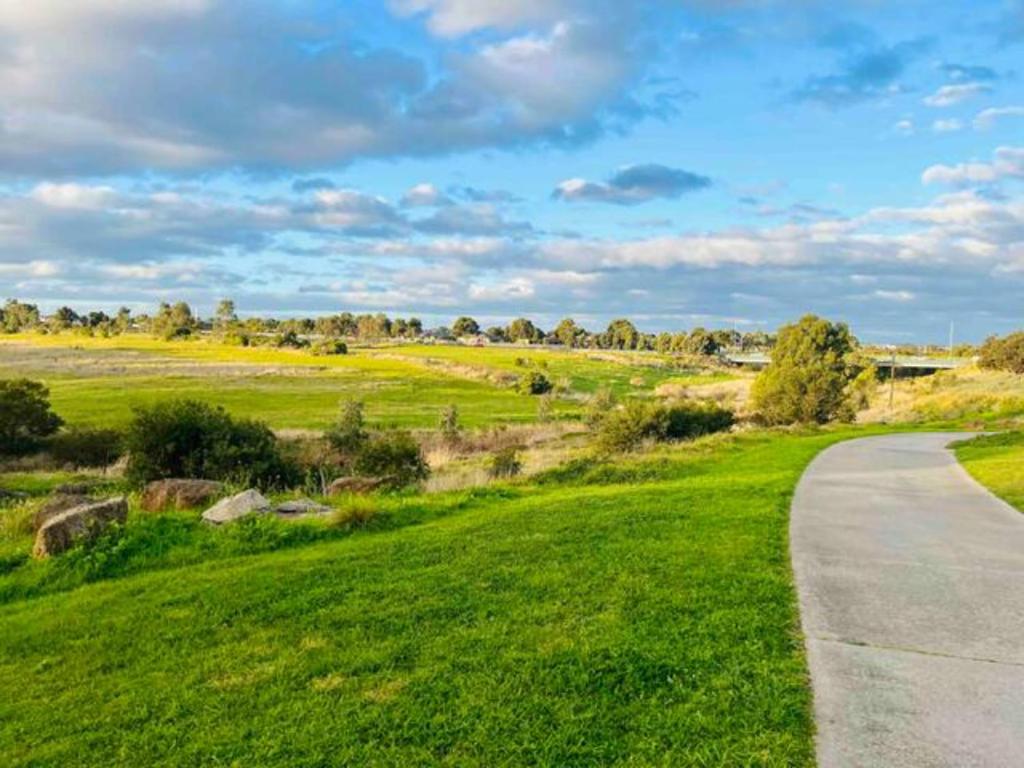 a road through a field with green grass at A spacious Vacation Home nearby Melbourne Airport in Caroline Springs