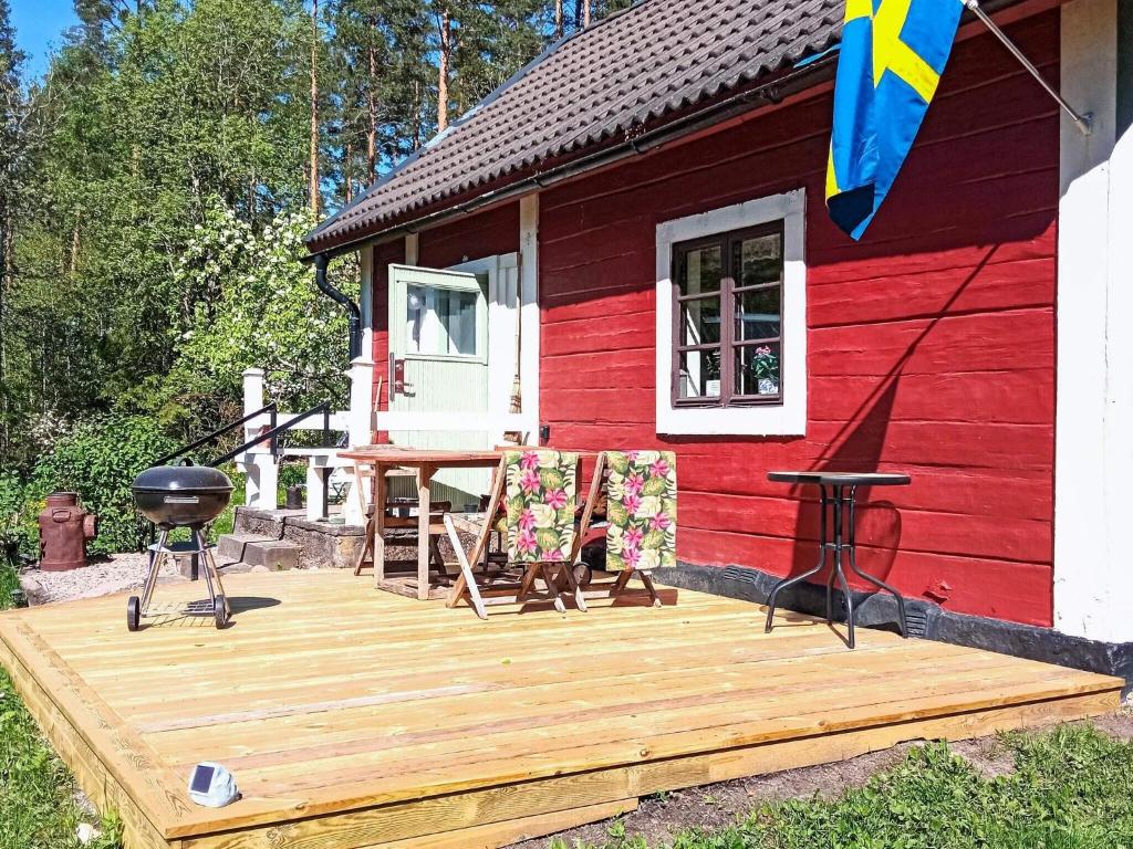 een rode hut met een houten dek en een grill bij Peaceful Country Home in Nykil in Nykil