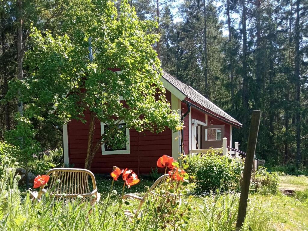 a small red cabin with red flowers in front of it at 4 person holiday home in NYKIL-By Traum in Nykil