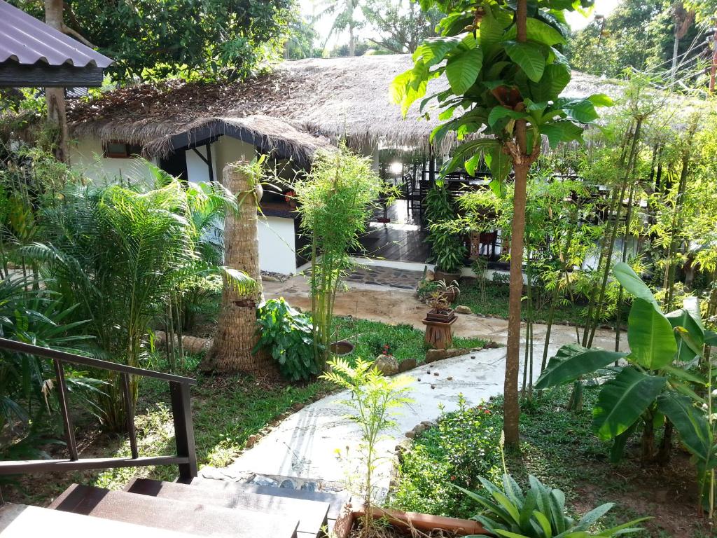 a garden in front of a house with a thatch roof at Lucky Gecko Garden in Ko Chang