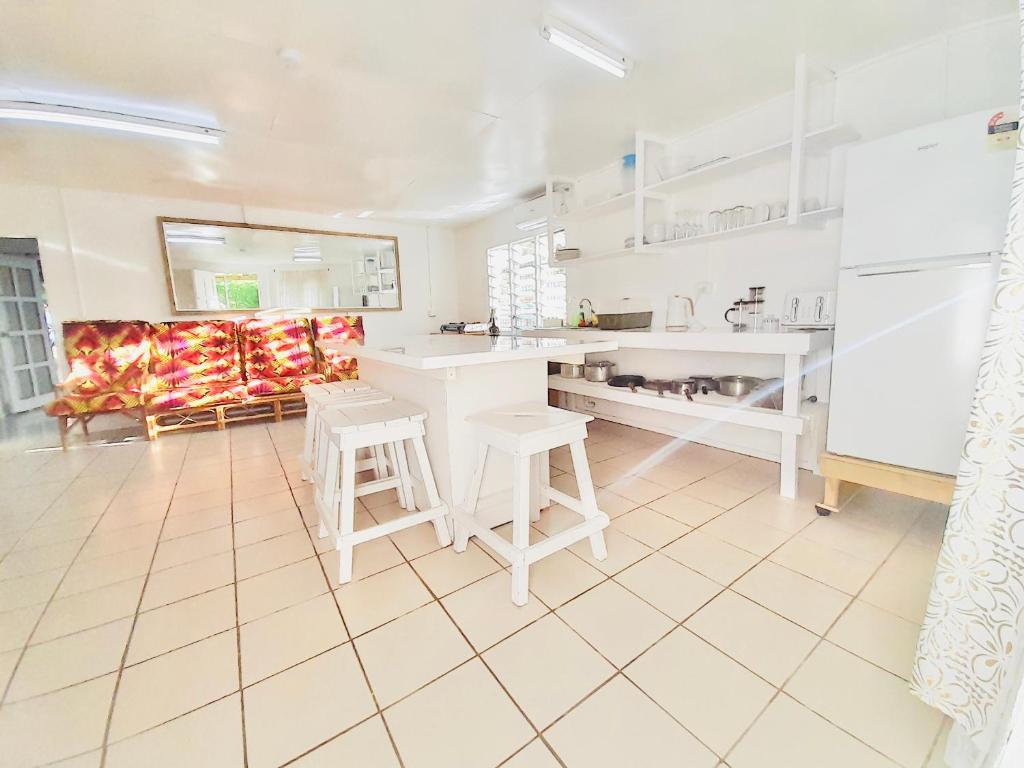 a kitchen with white counters and a table and chairs at Tonga Cottage - Entire Place with Aircon in Nuku‘alofa