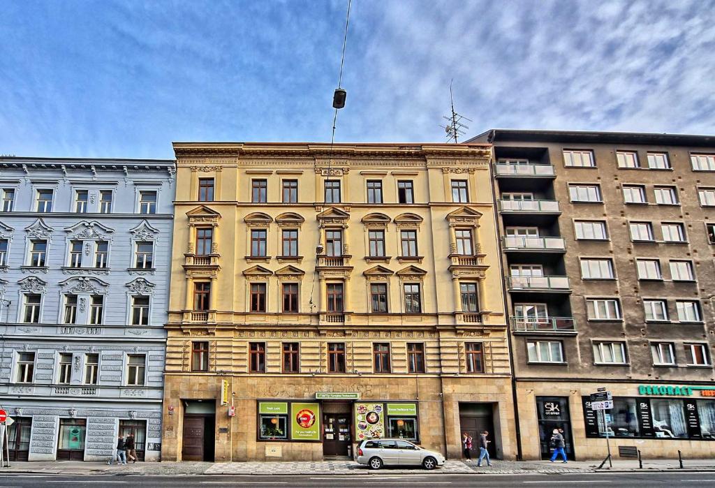 un gran edificio amarillo con un coche aparcado delante de él en Apartments At I.P.Pavlova en Praga