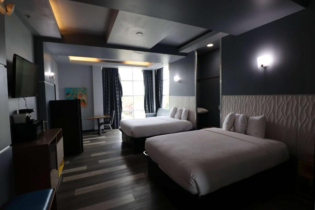 ein Hotelzimmer mit zwei Betten und einem Fernseher in der Unterkunft Days Inn &amp; Suites by Wyndham Milwaukee in Milwaukee