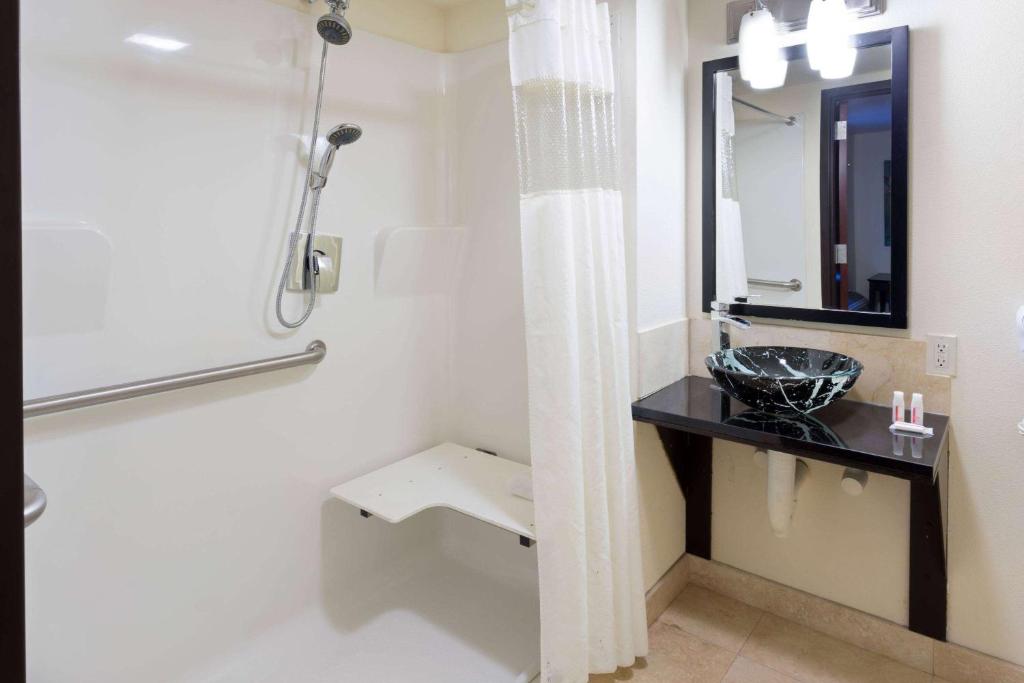 ein Badezimmer mit Waschbecken und Spiegel in der Unterkunft Days Inn &amp; Suites by Wyndham Milwaukee in Milwaukee