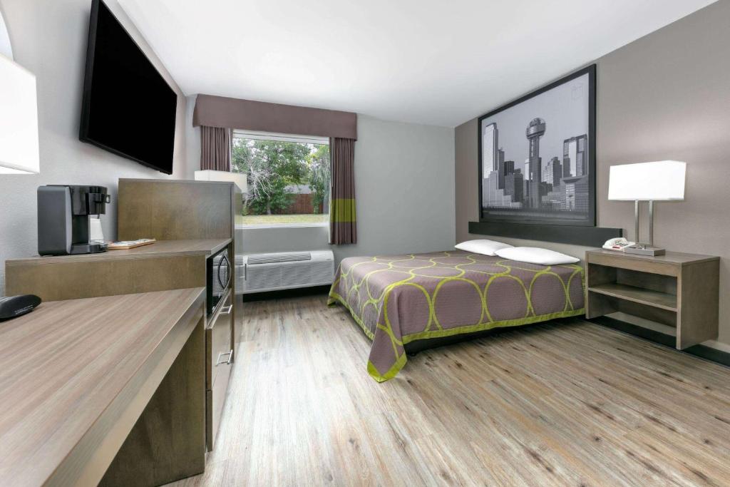 Una habitación de hotel con una cama y un televisor de pantalla plana. en Super 8 by Wyndham Waxahachie TX, en Waxahachie