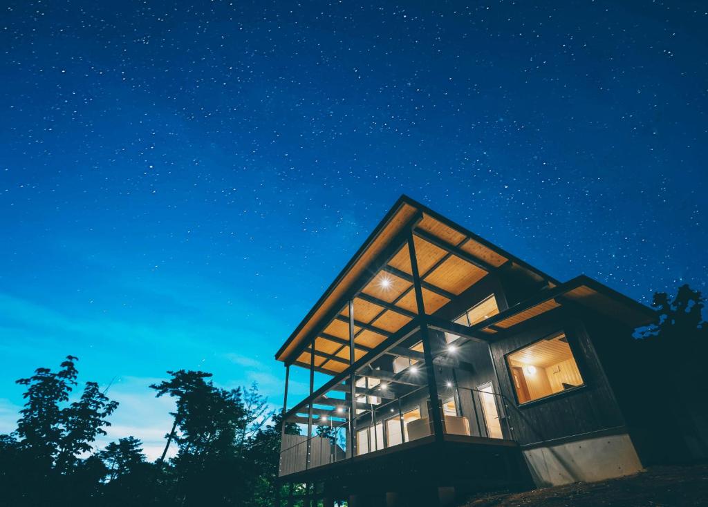 a glass house in the woods at night at お子さま連れ歓迎 森のやさしいサウナ付き一棟貸し -ご家族ご夫婦限定- in Komoro