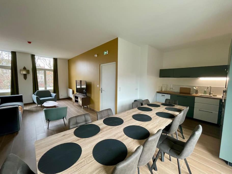 Cette chambre comprend une grande table et des chaises en bois. dans l'établissement Séjour Art Nouveau au coeur de Wazemmes, à Lille