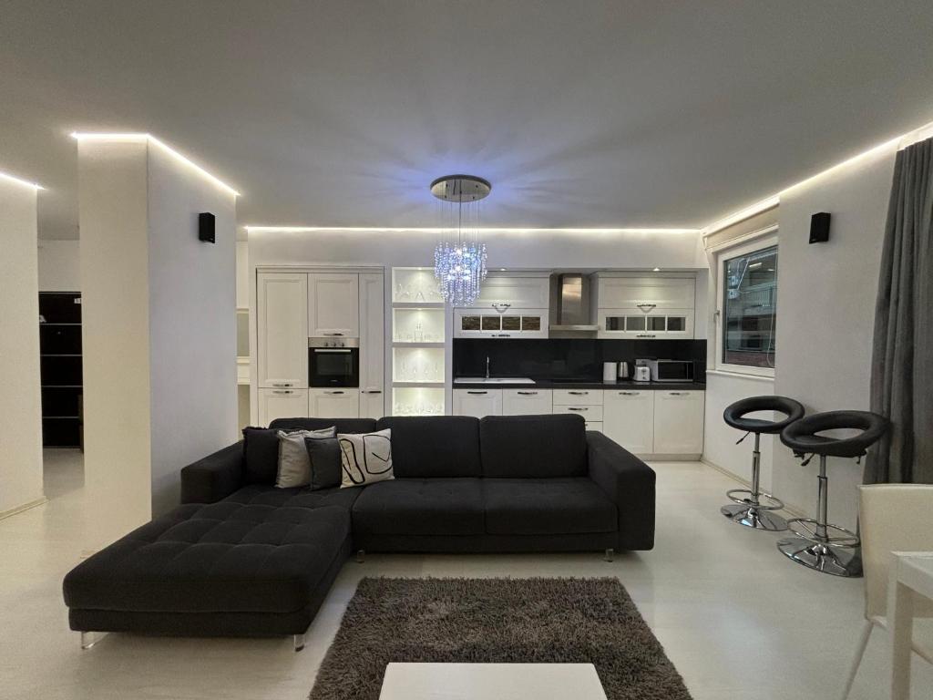 a living room with a black couch and a kitchen at TAM Serviced 2BDR Apartment City Center No6 in Tirana