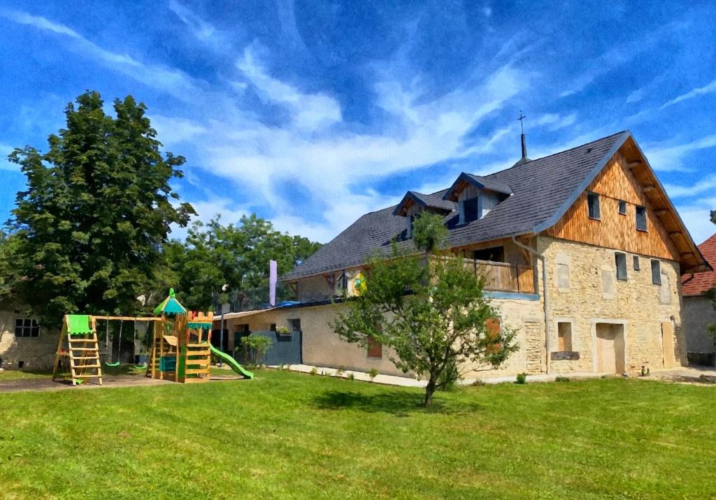 une grande maison avec une aire de jeux dans la cour dans l'établissement Gîte du petit ourson - Vue jardin -, à Guyans-Durnes