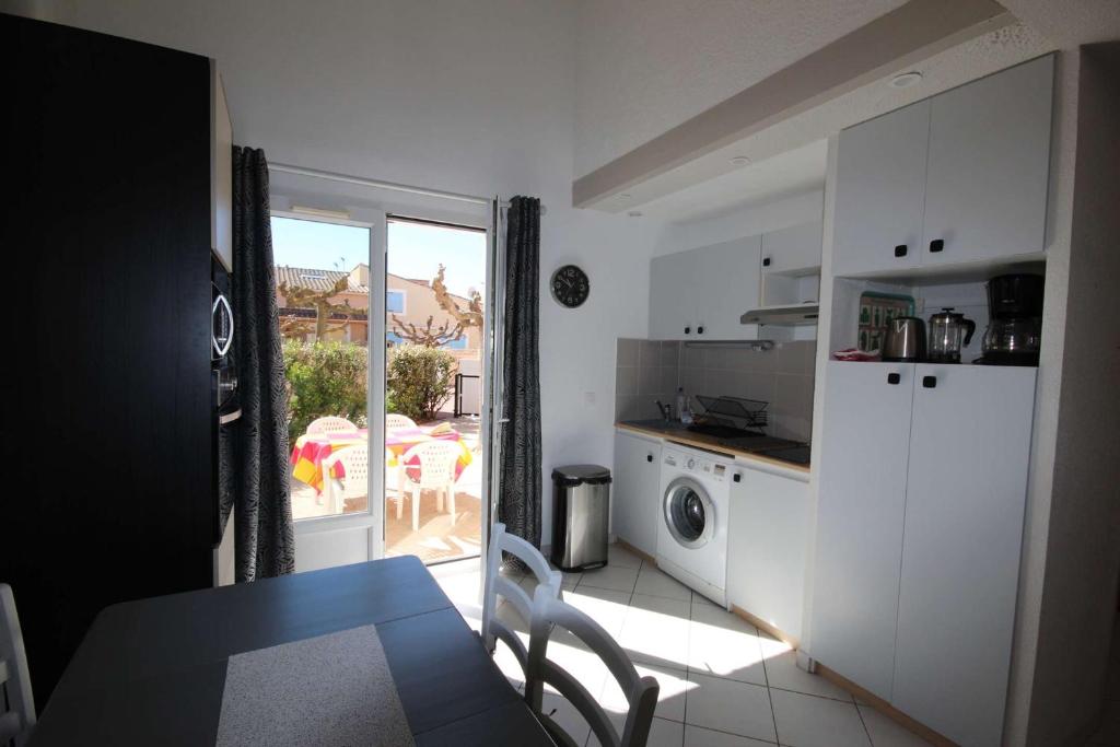 kuchnia ze stołem i drzwi na patio w obiekcie Villa plein sud, 4 couchages, en résidence LES ONDINES avec piscine commune, 500 m de la mer LROND28 w mieście Portiragnes