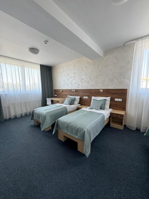a hotel room with two beds and windows at Sport hotel Sletiště in Kladno
