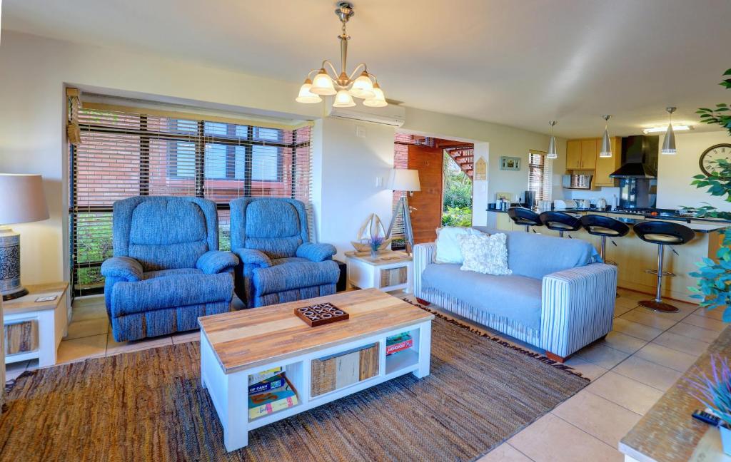 a living room with two blue chairs and a table at Between The Milkwoods in Wilderness