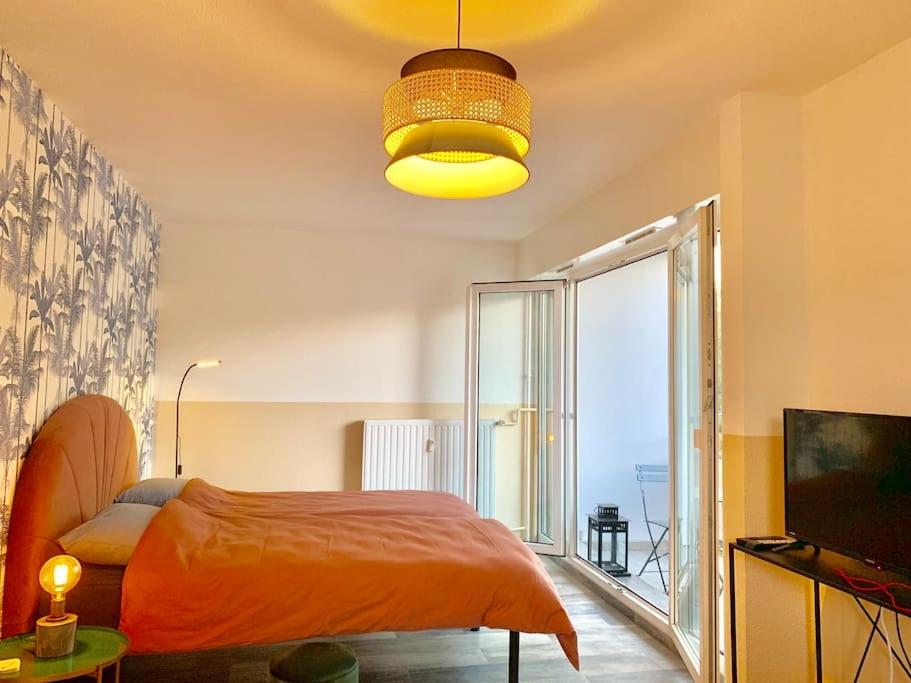 - une chambre avec un lit orange et une grande fenêtre dans l'établissement Appart Melvyn Chanael - proche gare, à Saint-Louis