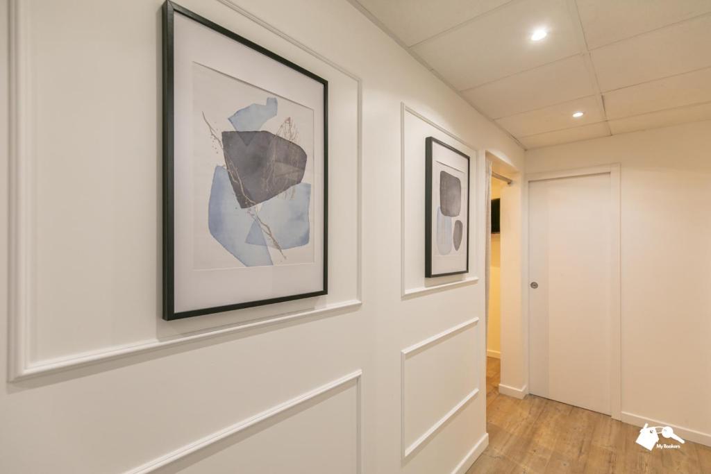 un couloir avec deux tableaux encadrés sur un mur dans l'établissement MBA - Beslay - Splendide Appartement Paris Centre, à Paris