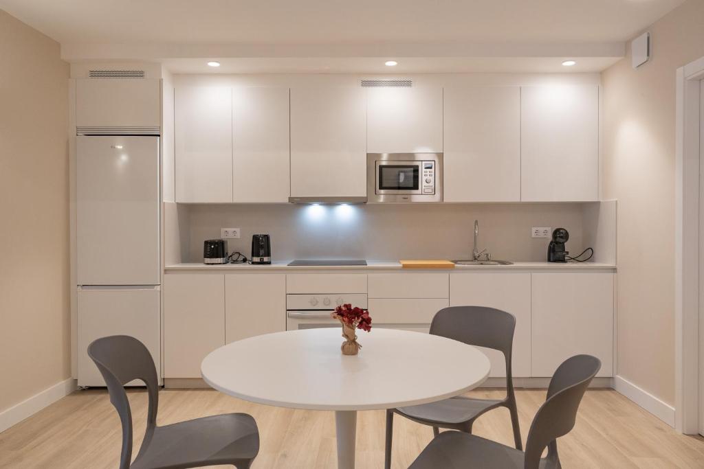 a white kitchen with a white table and chairs at HALO Vigo TRES in Vigo