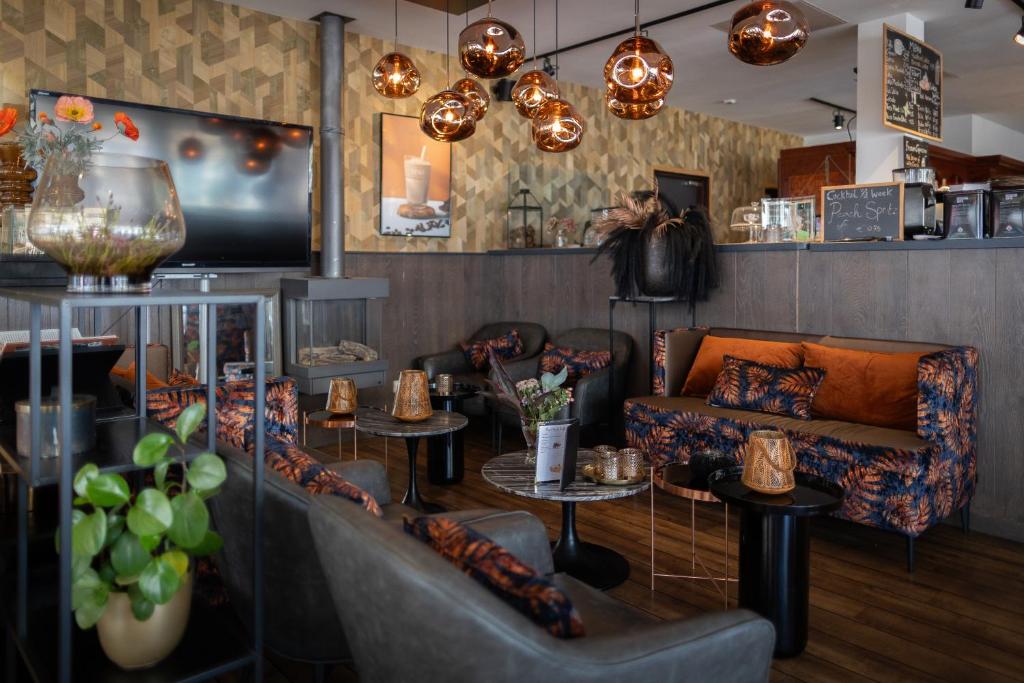 een woonkamer met banken, tafels en verlichting bij Hotel Tesselhof in De Koog